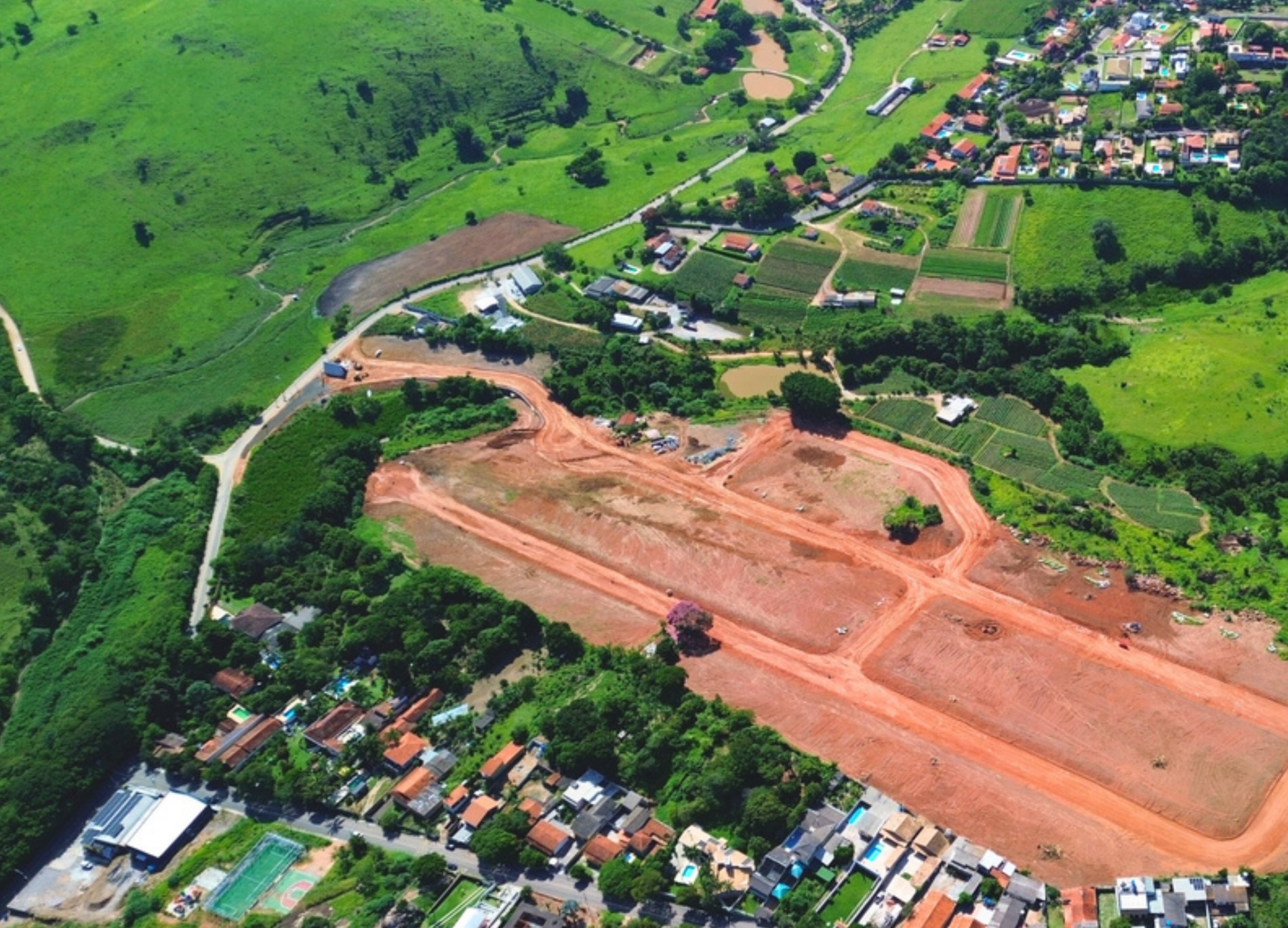 Vista aérea das obras do loteamento com o bairro e as montanhas ao fundo